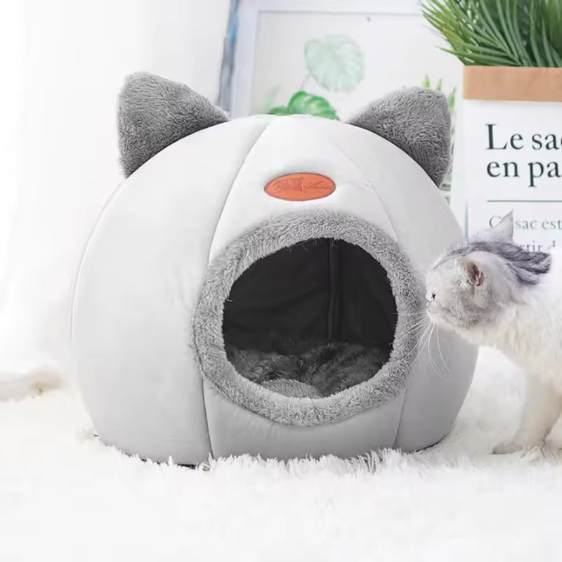 Cat-shaped pet cave with a cat peeking out on a white surface